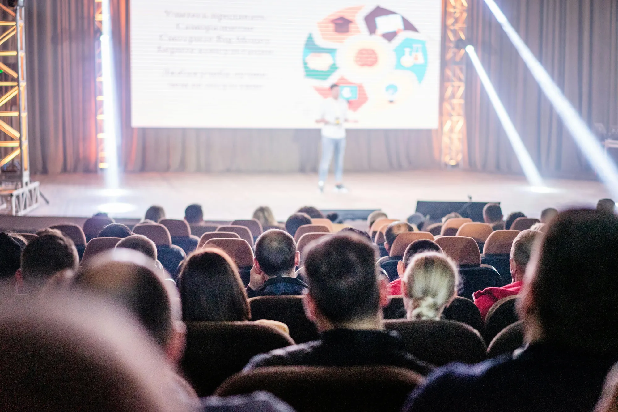 A blurred presenter speaking to an audience at a live event